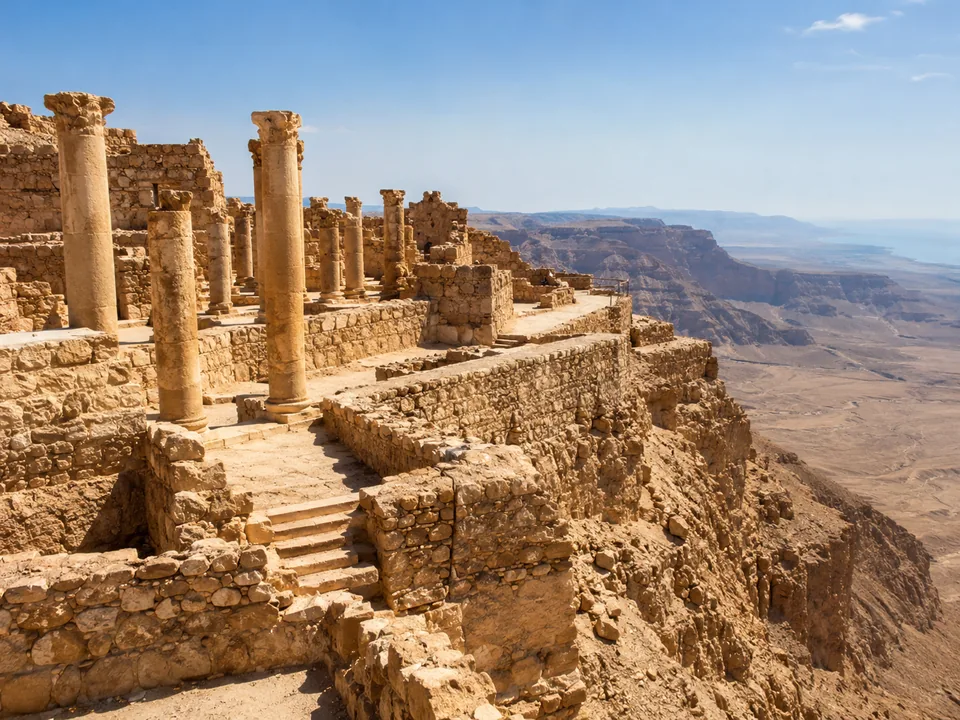 Stone columns and terraced ruins on a cliff edge above the desert