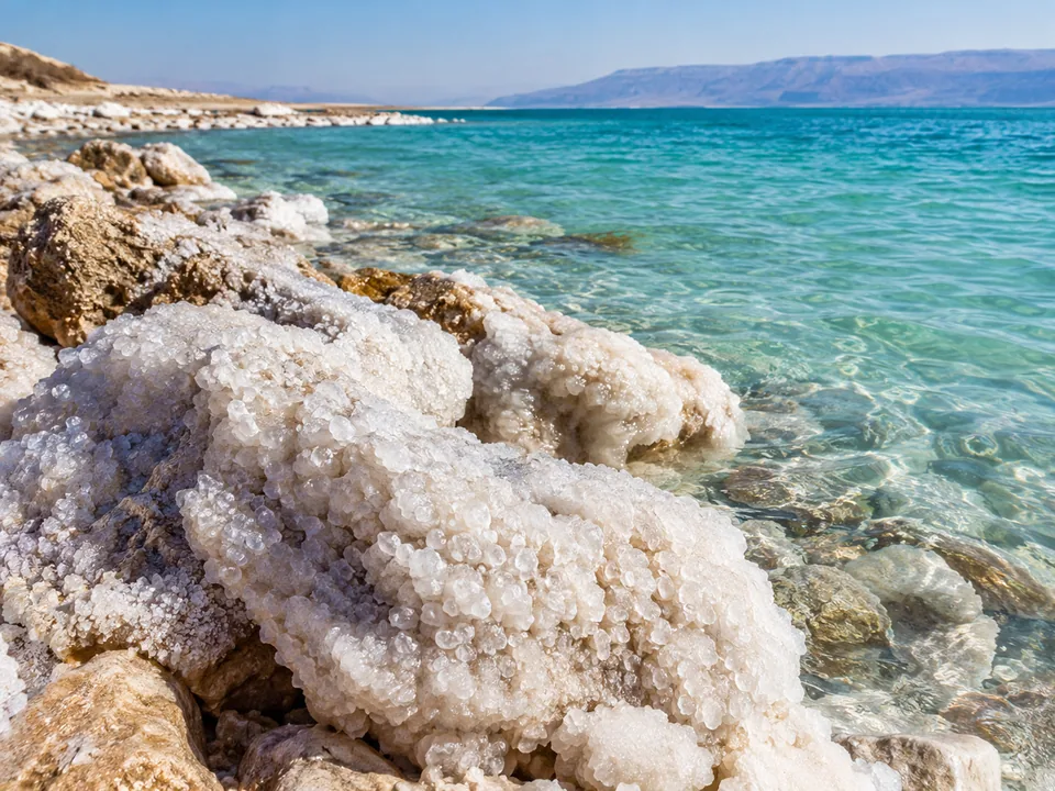 White salt crystals crusting the stones at the edge of turquoise water